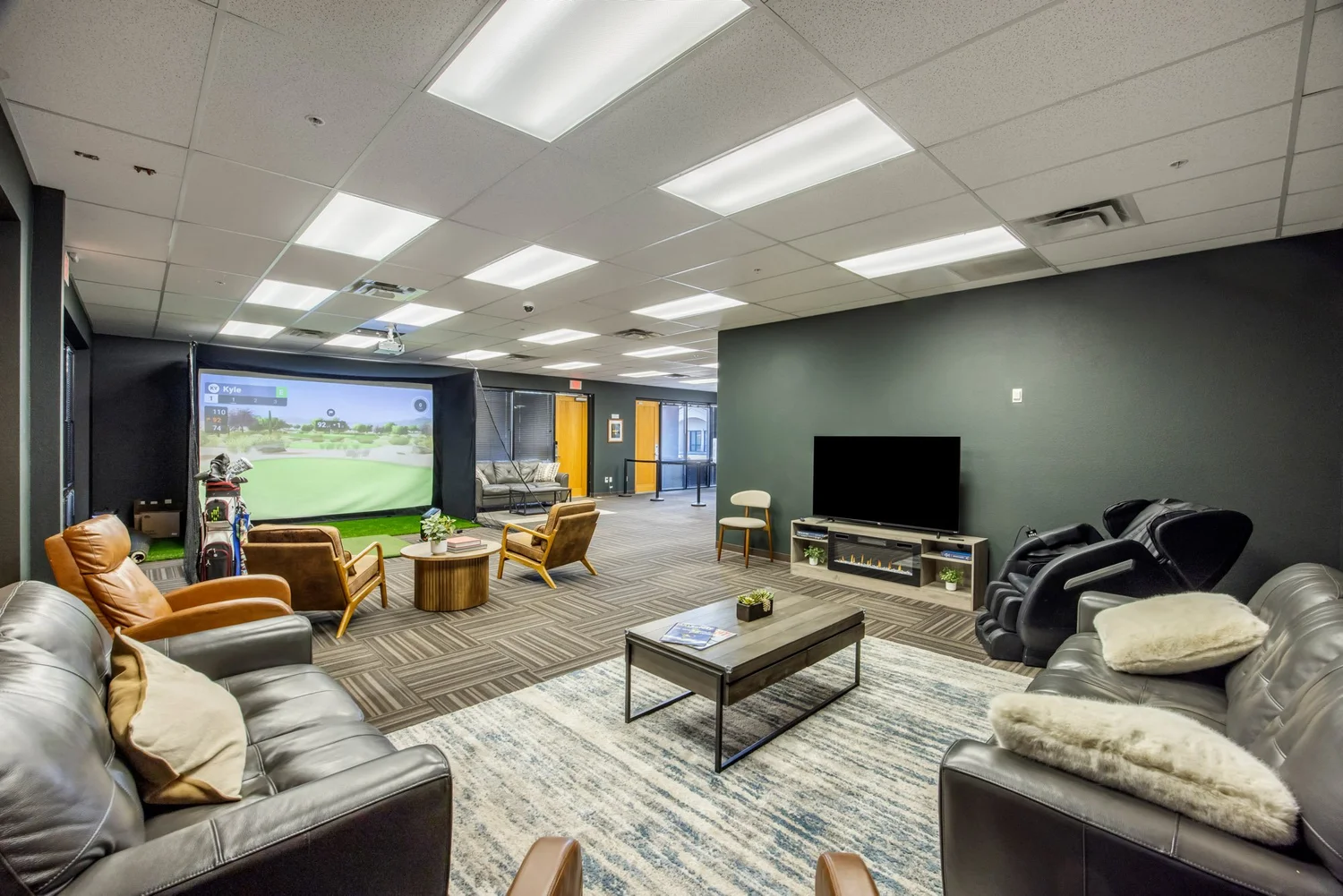 Wide shot of the Jaybird lounge showing the golf bay, leather sofas, big-screen TV, and the Redbird FMX area