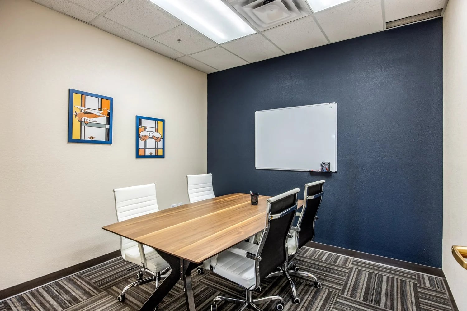 Briefing room with a navy accent wall, large whiteboard, walnut conference table, executive chairs, and aviation-themed art
