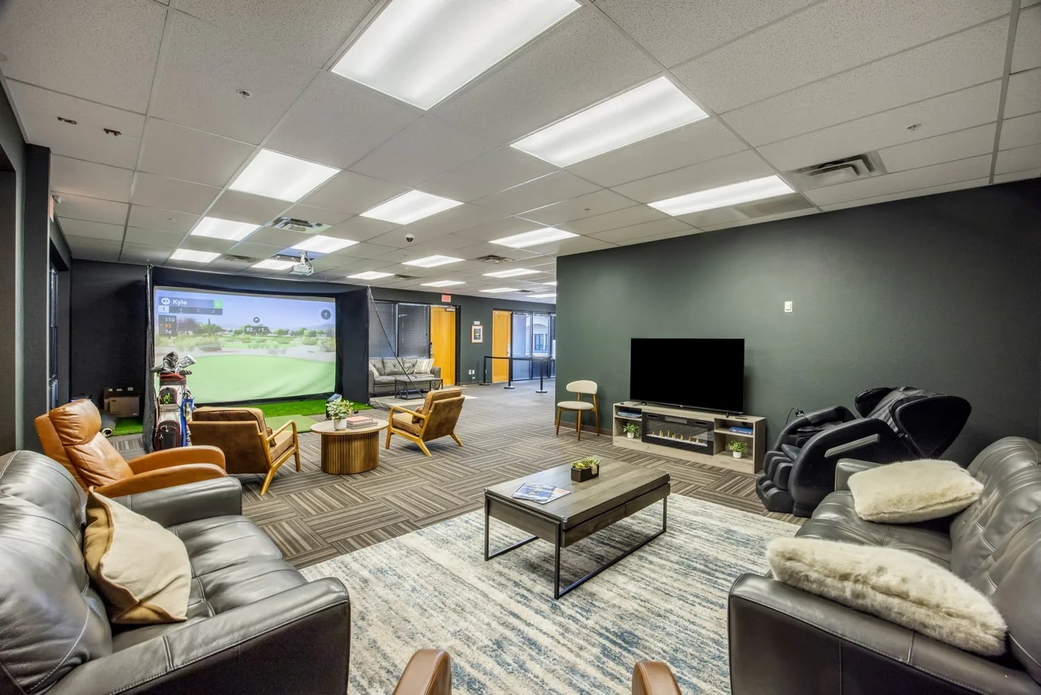 Wide shot of the Jaybird lounge showing the golf bay, leather sofas, big-screen TV, and the Redbird FMX area