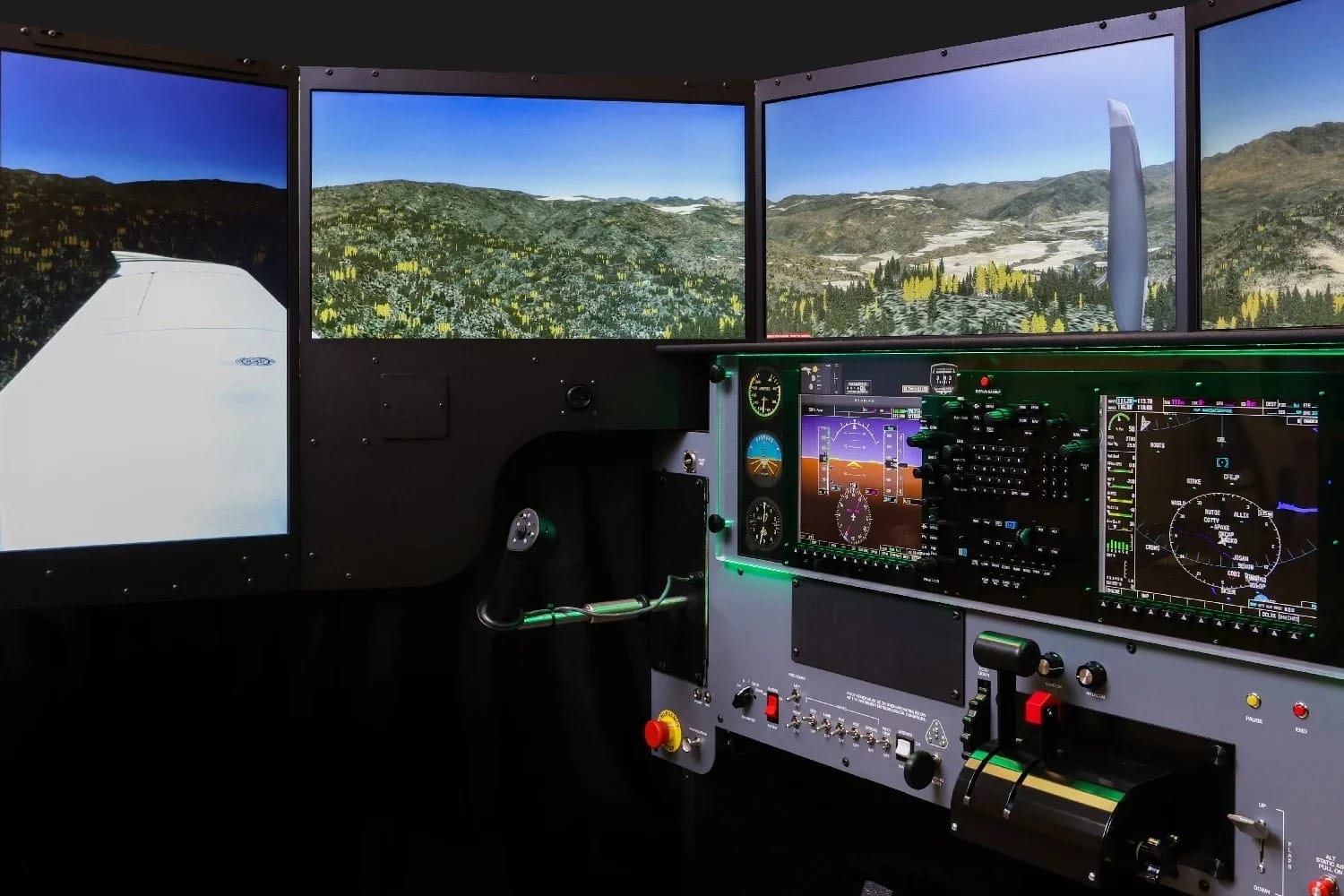 Wide product shot of the Redbird FMX cockpit interior with wraparound visuals showing alpine terrain and a Cessna 172 wing